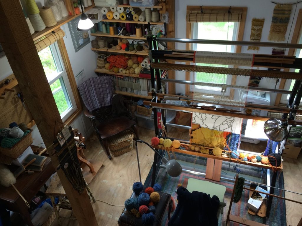 View from the loft. The yarn on the shelves is my stash of linen yarn, as well as some of the yarns I’m using for the current tapestry on the lower shelves. The yarn over the window is mostly cotton. The wool lives in plastic bins in the loft.