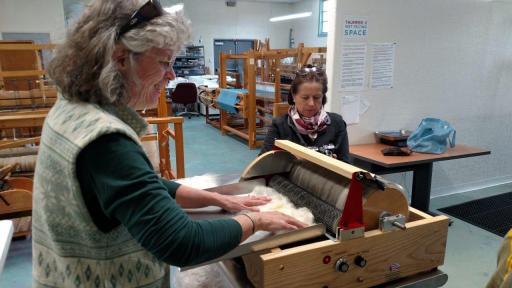 Peggy running the very first fiber into the carder. Olimpia Newman, the EVFAC Director of Development looking on